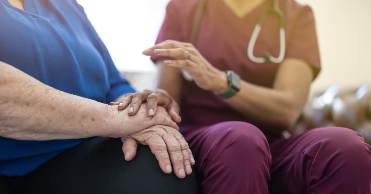 Une infirmière réconforte un patient âgé en lui tenant la main