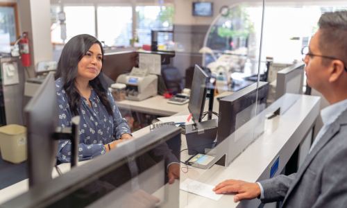 Un employé de banque aide un homme à sortir d'un guichet 