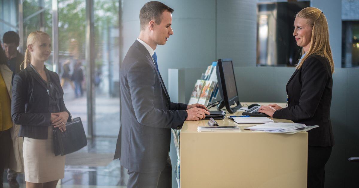 Caissier de banque s'adressant à un homme dans la file d'attente 