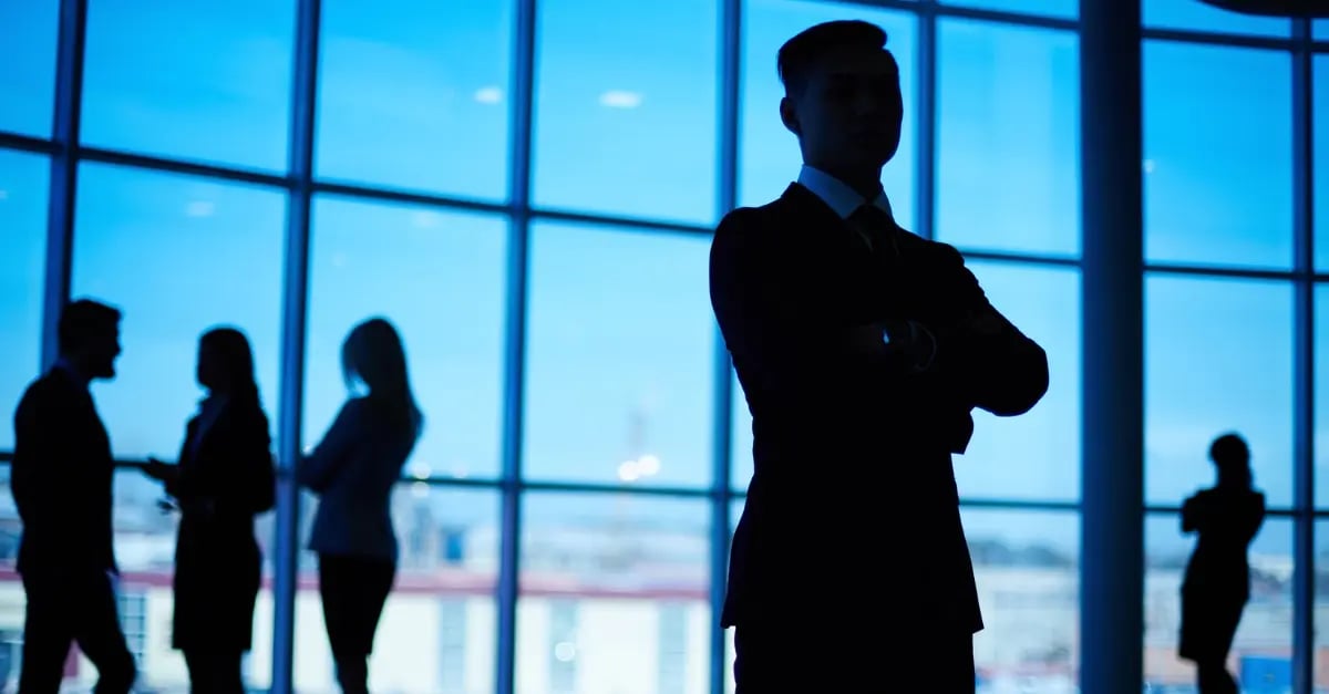 Silhouette d'un homme avec les bras croisés et des personnes debout autour de lui