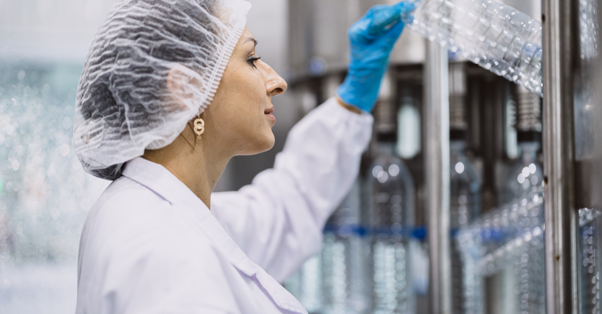 Femme avec une résille portant une blouse de laboratoire examinant du plastique 