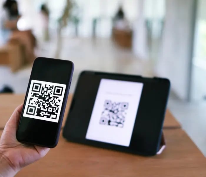 Personne scannant le code QR sur une tablette avec un iPhone 