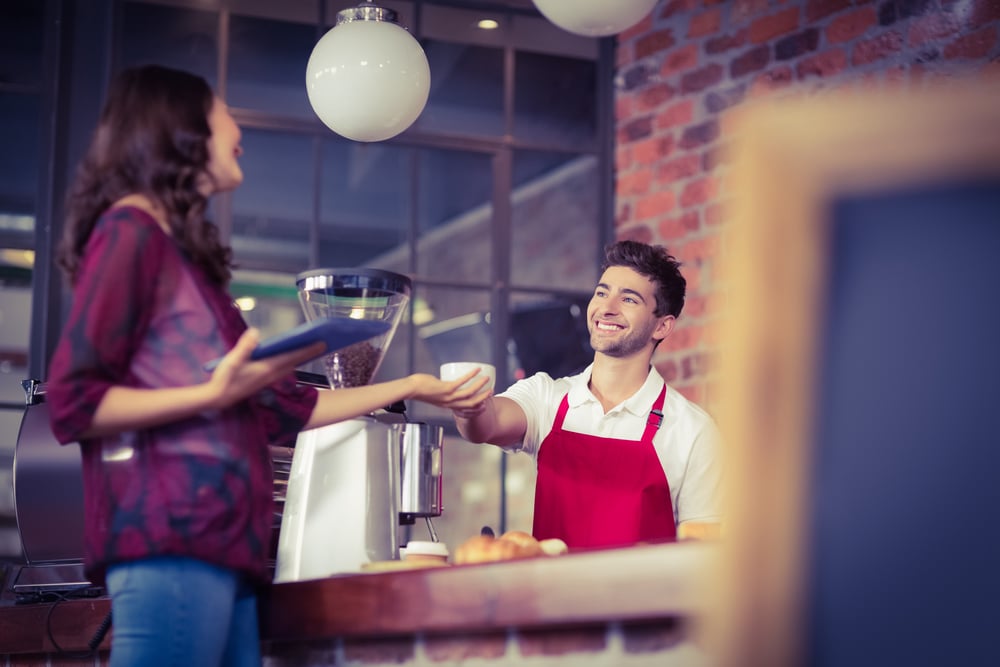 Serveur souriant servant un client au café-1