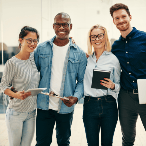 Équipe debout et souriante avec des appareils mobiles à tablette