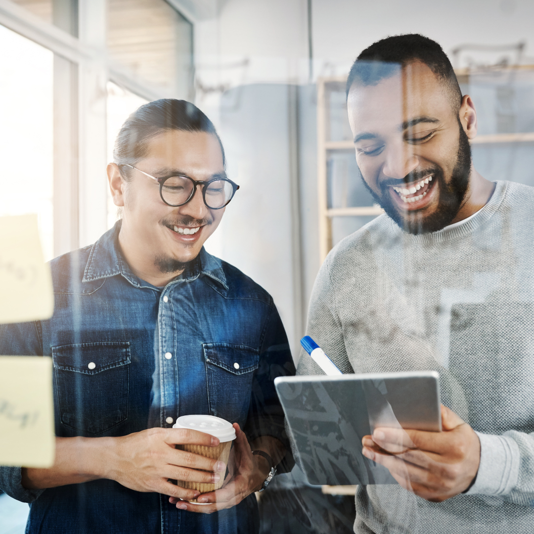 Deux collègues souriant et prenant des notes sur un iPad