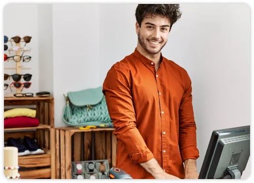 Employé du commerce de détail en chemise orange travaillant derrière un comptoir