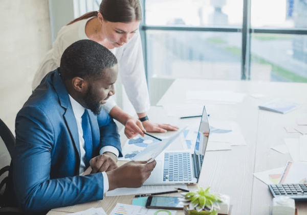 Une femme d'affaires travaille avec son patron pour envoyer des chèques via le cloud.