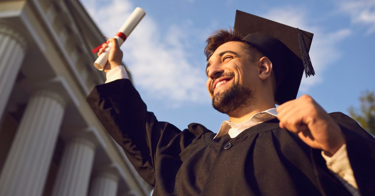 Man graduating from college holding up his diploma 