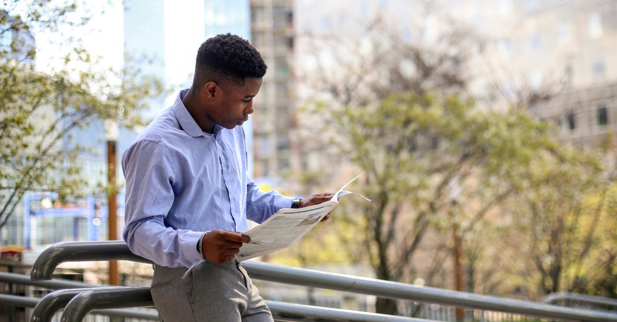 Homme lisant un journal à l'extérieur