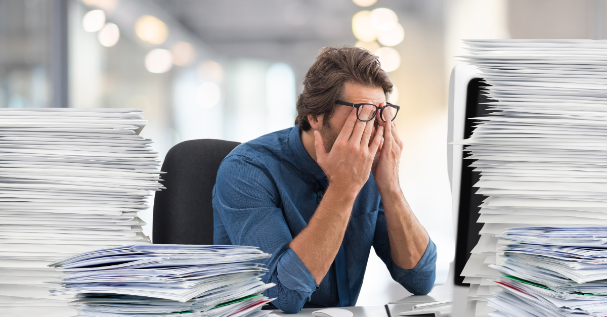 Principal frustré entouré de piles de papier et de courrier 