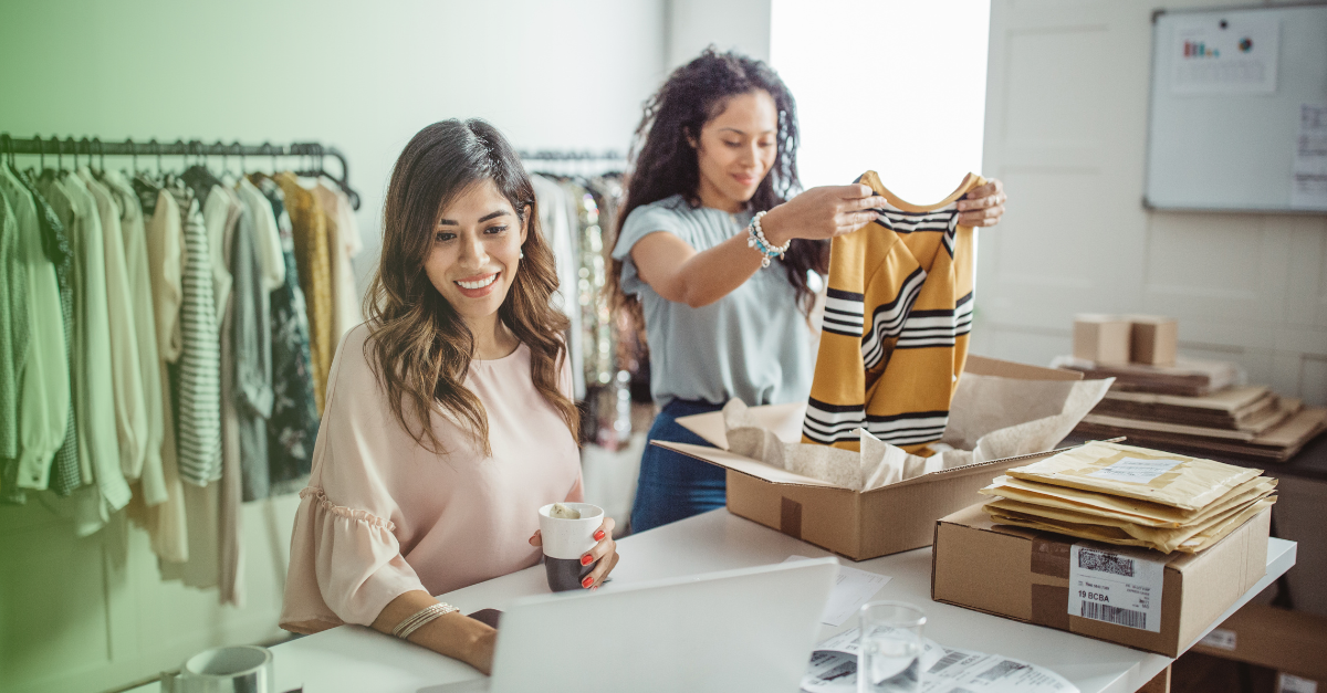 Two women packing clothing from their small business 