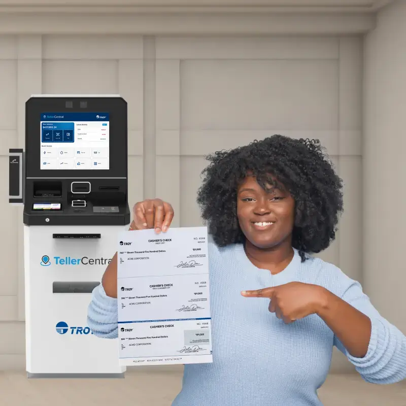 Femme tenant un chèque de banque devant un kiosque libre-service TellerCentral